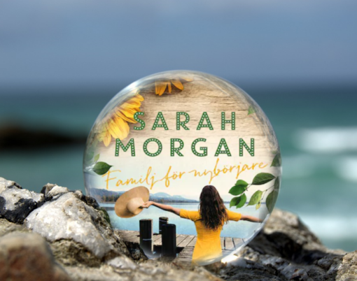Omslaget till boken Familj för nybörjare av Sarah Morgan inuti en liten glaskula som är på en havsklippa med havet i bakgrunden.